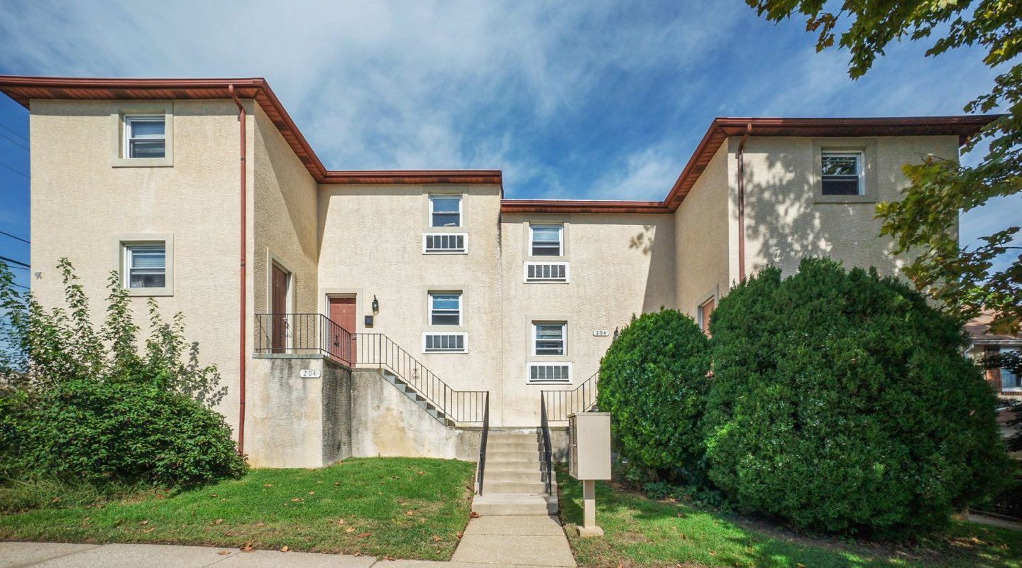 Photo of a two or three story building with plenty of greenery around the building
