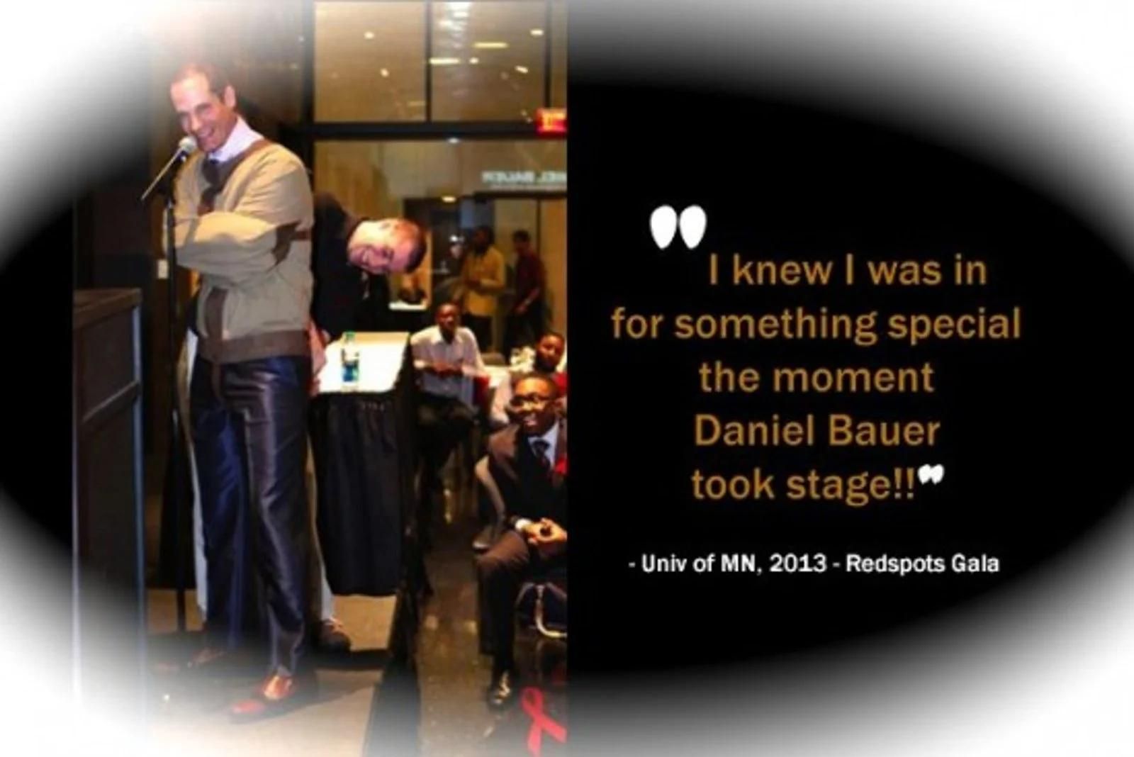 Man speaking at a podium beside a woman with a quote about seeing Daniel Bauer take the stage