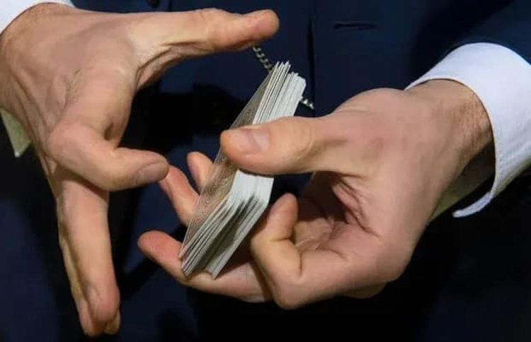 Two hands manipulating a deck of cards against a dark background