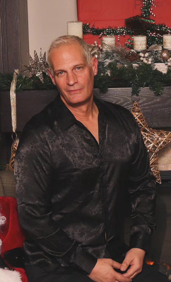 Daniel Bauer seated indoors before a decorated Christmas tree