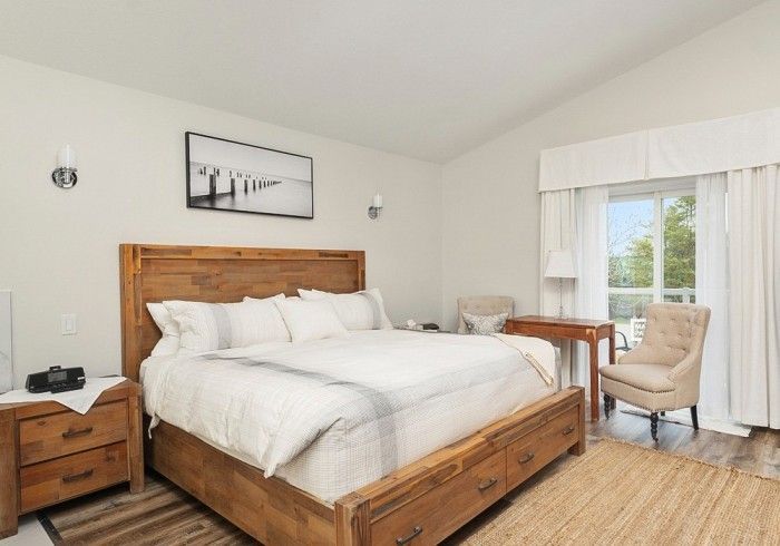 A bedroom with a king size bed , nightstand , chair and desk. Lakeshore Inn Bed & Breakfast