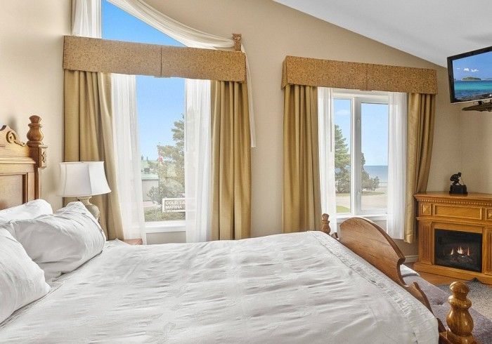 A bedroom with a king size bed , fireplace and television. Lakeshore Inn Bed & Breakfast
