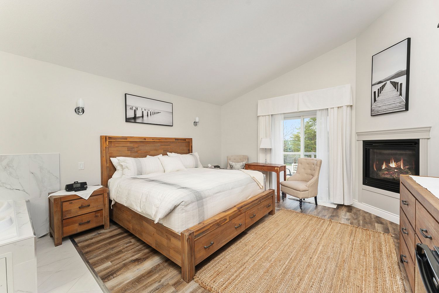 A bedroom with a king size bed, desk, balcony, fireplace, and lake view. Lakeshore Inn Bed & Breakfast