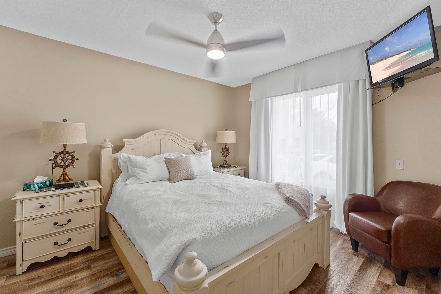 A bedroom with a queen bed , dresser , chair and television. Lakeshore Inn Bed & Breakfast