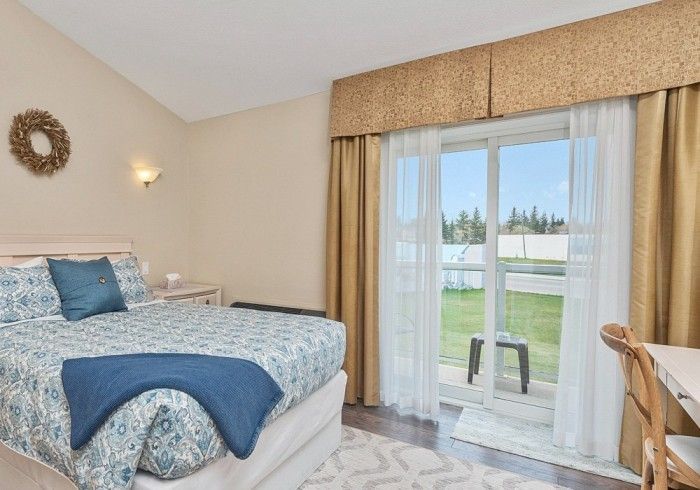 A bedroom with a king size bed and a sliding glass door Lakeshore Inn Bed & Breakfast
