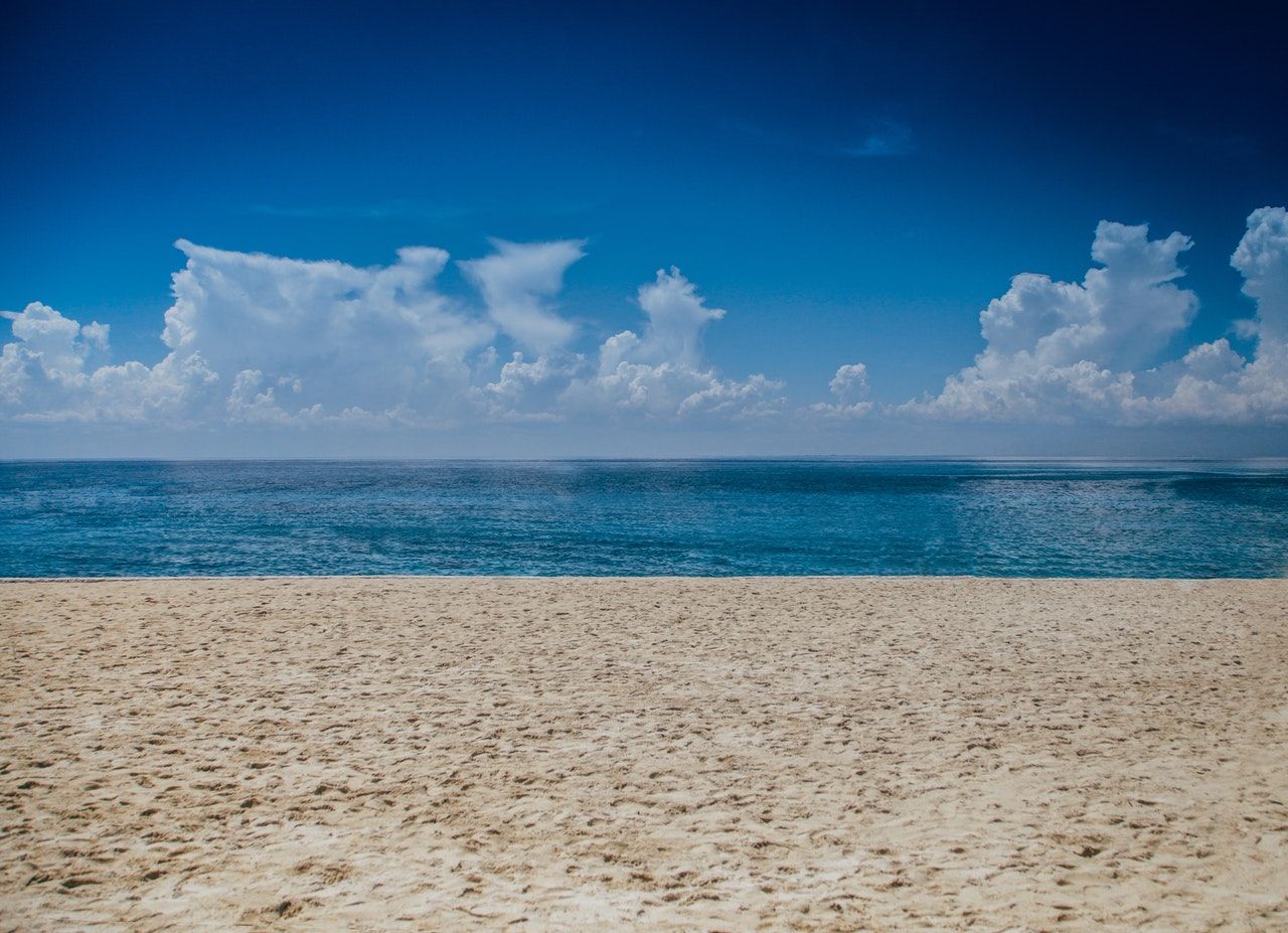 There is a beach with a blue sky and clouds in the background.