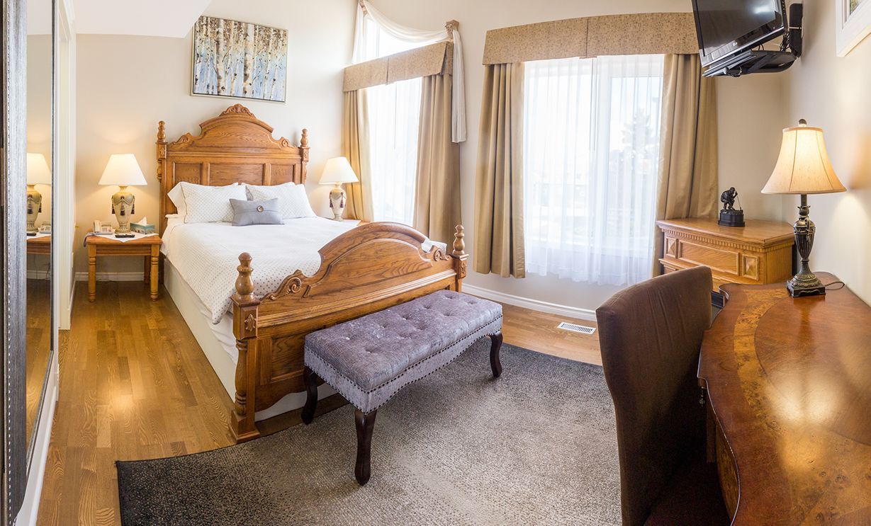 A hotel room with a king size bed , desk , chair and television. Lakeshore Inn Bed & Breakfast