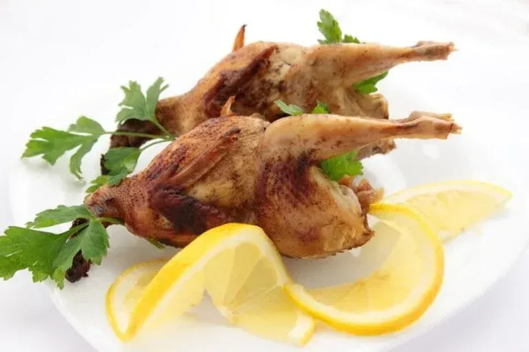 A white plate topped with fried quail and lemon slices