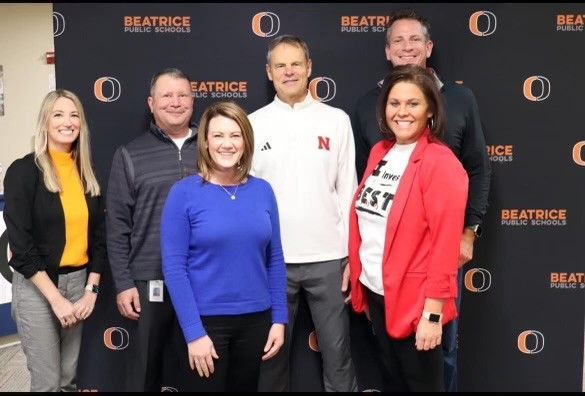 A group of people posing in front of a wall that says beatrice