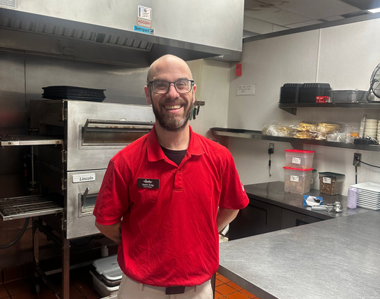 server smiling holding trays of food