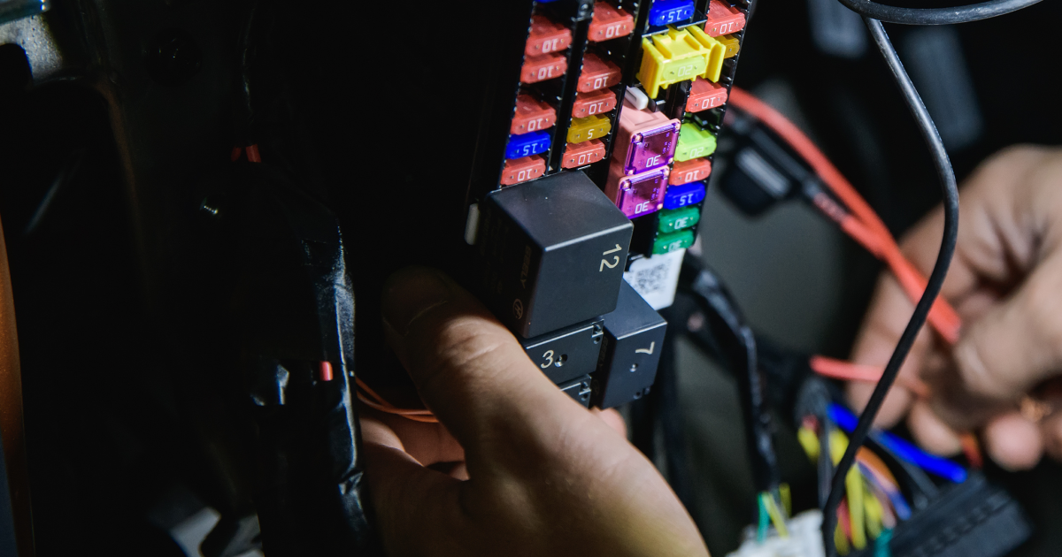 Hands wiring a small electronics setup with colorful components and cables on a dark workbench | Quality Auto Repair Tire & Auto Sales