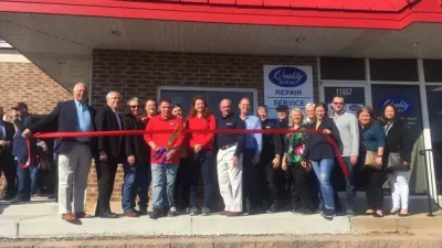 Group of people posing outside a storefront, holding a red ribbon at a ribbon-cutting ceremony. | Quality Auto Repair Tire & Auto Sales