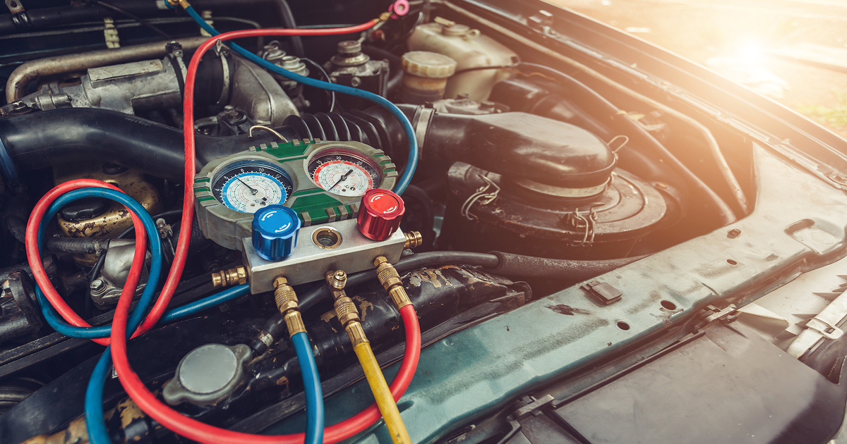 Car engine being serviced with red and blue hoses connected to pressure gauges under the hood | Quality Auto Repair Tire & Auto Sales
