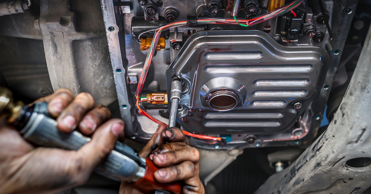 Hands using a tool to repair wiring on a vehicle's exposed engine component. | Quality Auto Repair Tire & Auto Sales