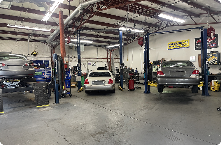 Auto repair shop with several cars on lifts and equipment in a large garage interior | Quality Auto Repair Tire & Auto Sales