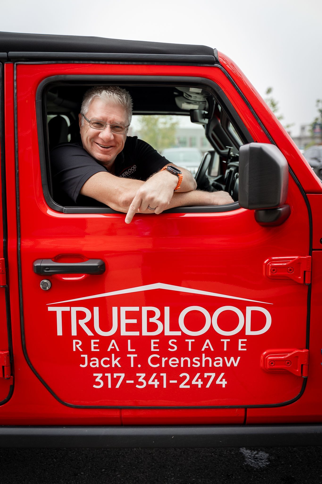 Man in red Jeep points, logo 
