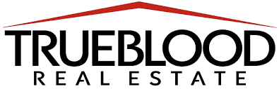 Trueblood Real Estate logo with the word Trueblood in large black font, a red roof shape above it, and the words Real Estate in smaller black font.