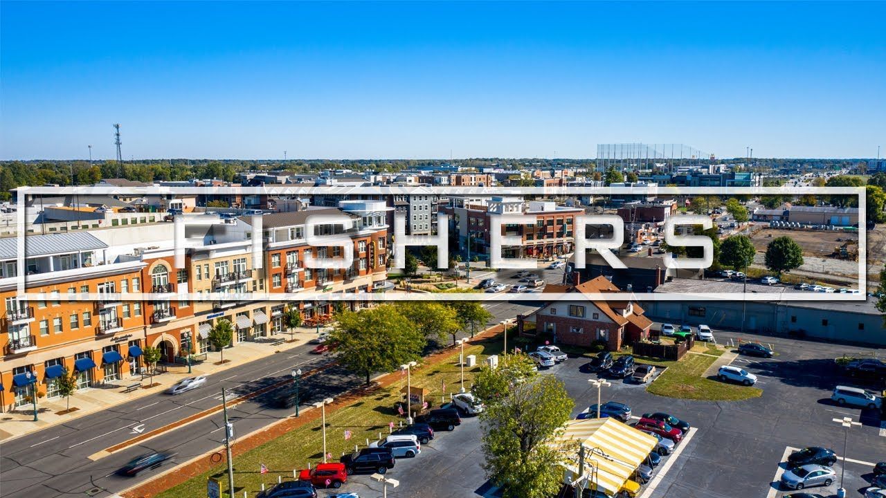 Aerial view of downtown Fishers, Indiana, with the town's name overlaid on the buildings and sky.