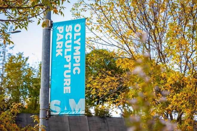 Blue “Olympic Sculpture Park” sign among autumn trees against a sunny sky