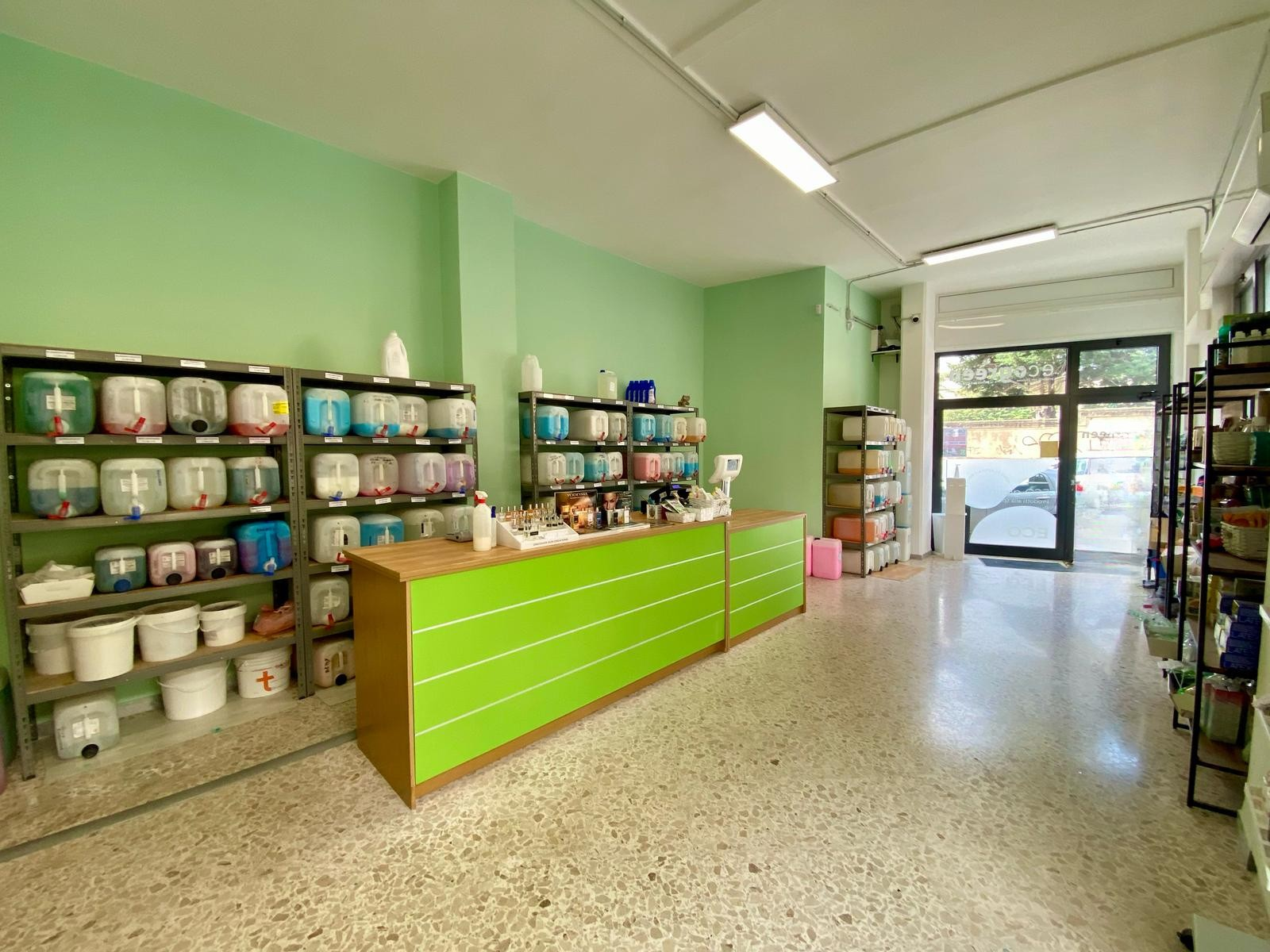 Un negozio con un bancone verde e scaffali pieni di secchi.