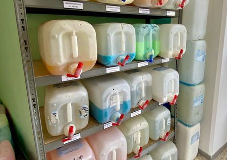 Uno scaffale pieno di contenitori di plastica con rubinetti.