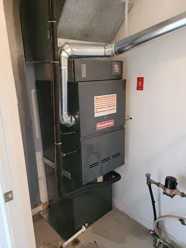 Basement utility area with a black furnace, silver ducts, and a small window with curtains.