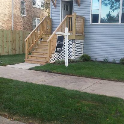 A house with a wooden deck and stairs is for sale
