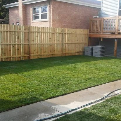 A backyard with a wooden fence and a deck