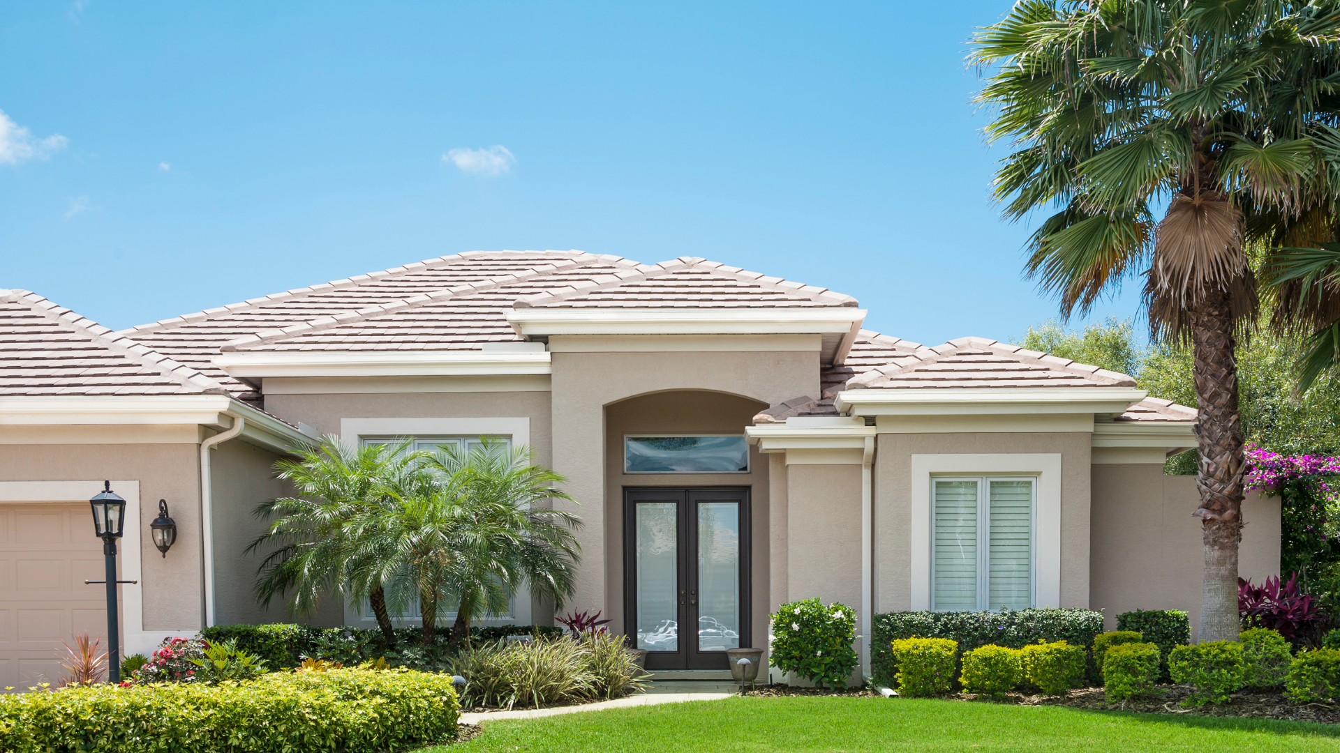 Gray house with a dark roof and white trim under a blue sky.
