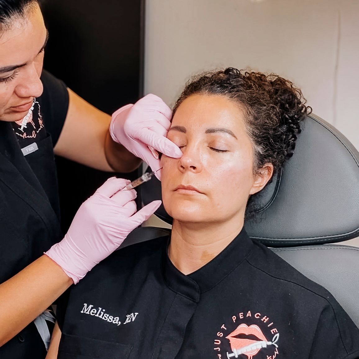 Woman receiving a facial injection. Medical professional in pink gloves. Clinic setting.