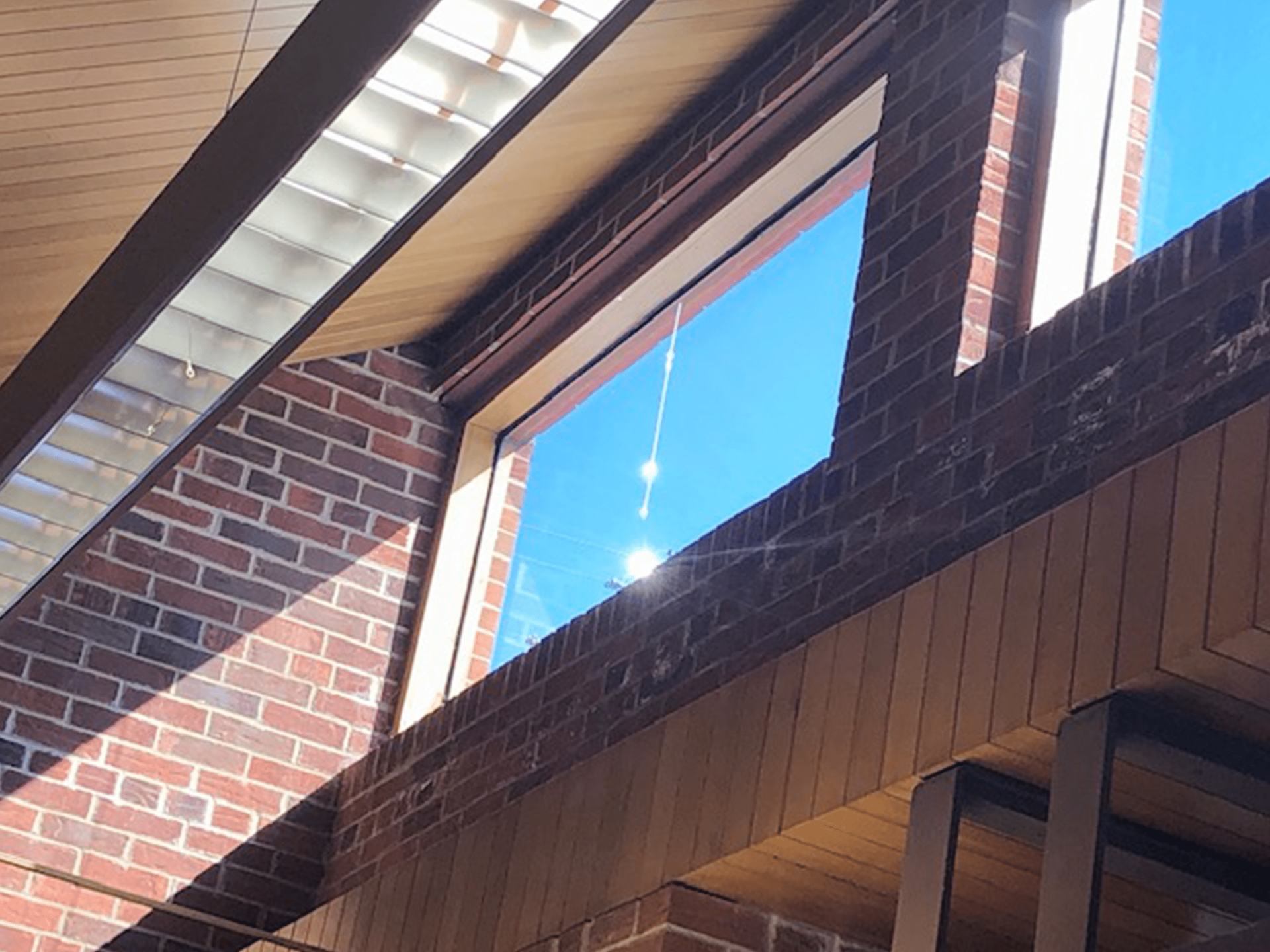 Brick building interior with large windows showing a bright blue sky outside.