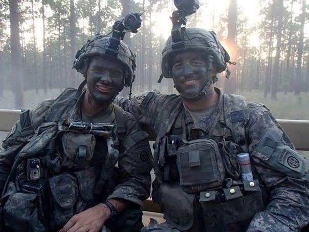 Two soldiers are posing for a picture with their faces painted black