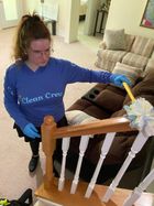 A person wearing yellow gloves is cleaning a bathroom sink with a spray bottle.