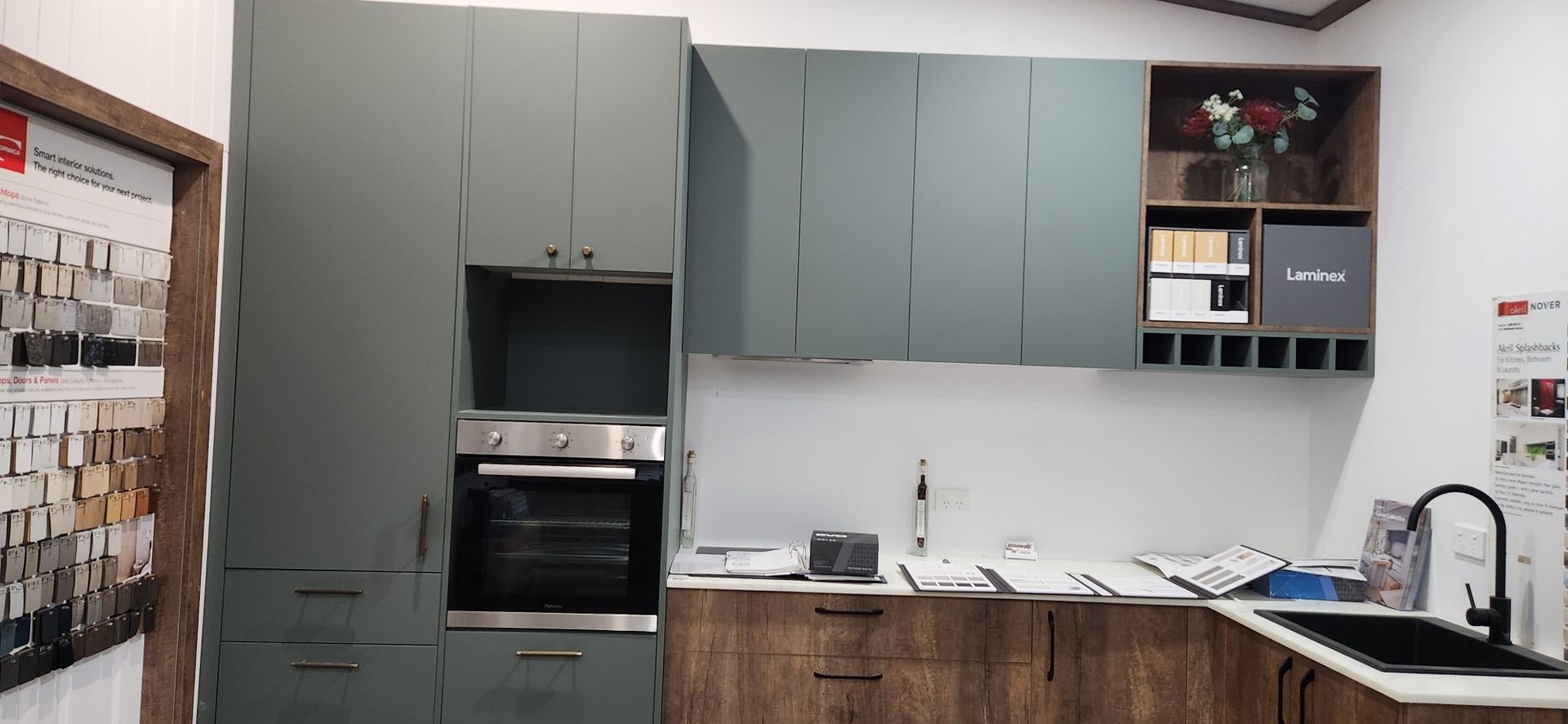 Small office kitchenette with gray cabinets, sink, counter, printer, and bulletin board.