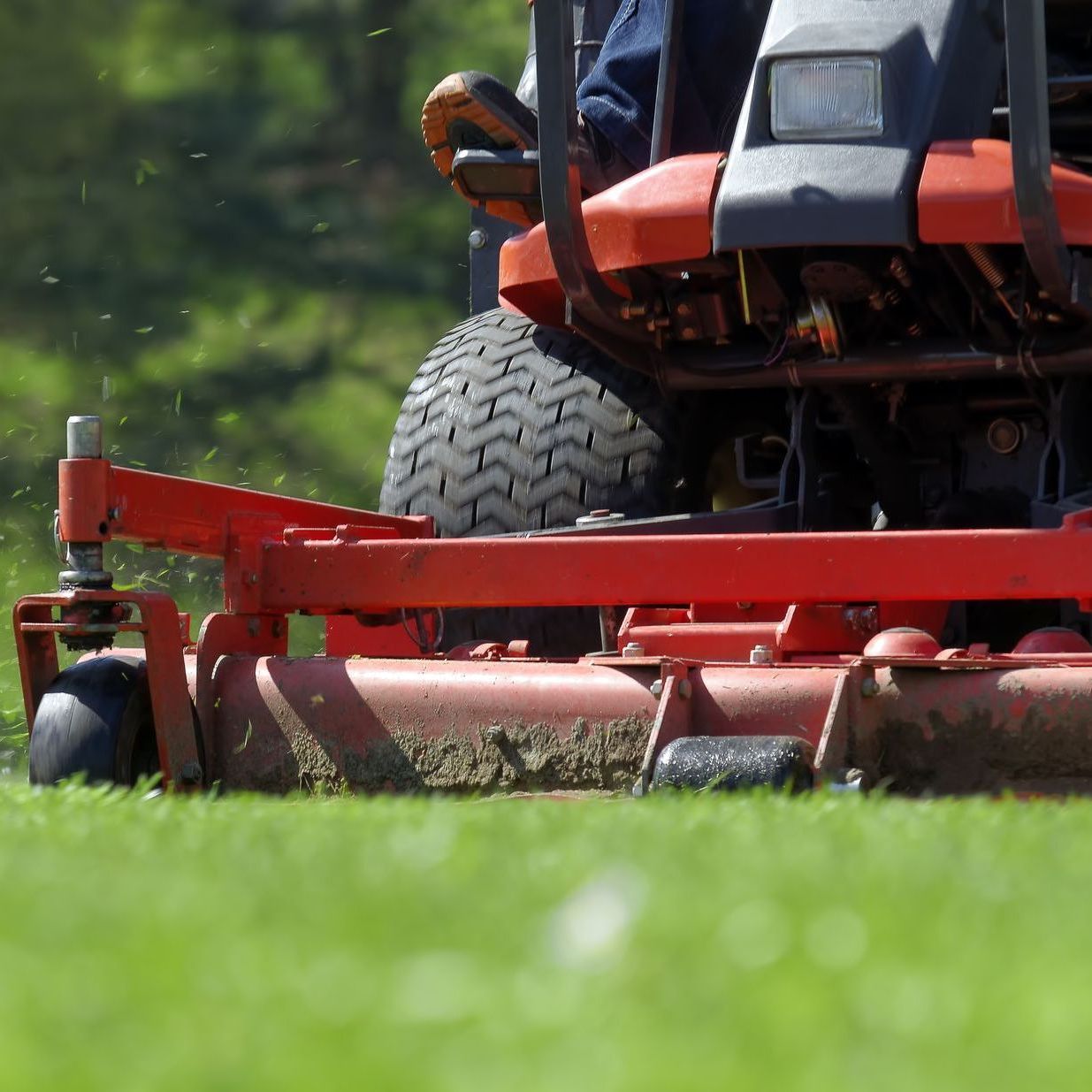 a person is riding a red lawn mower on a lush green field
