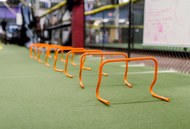 A row of orange hurdles are lined up on a green field.