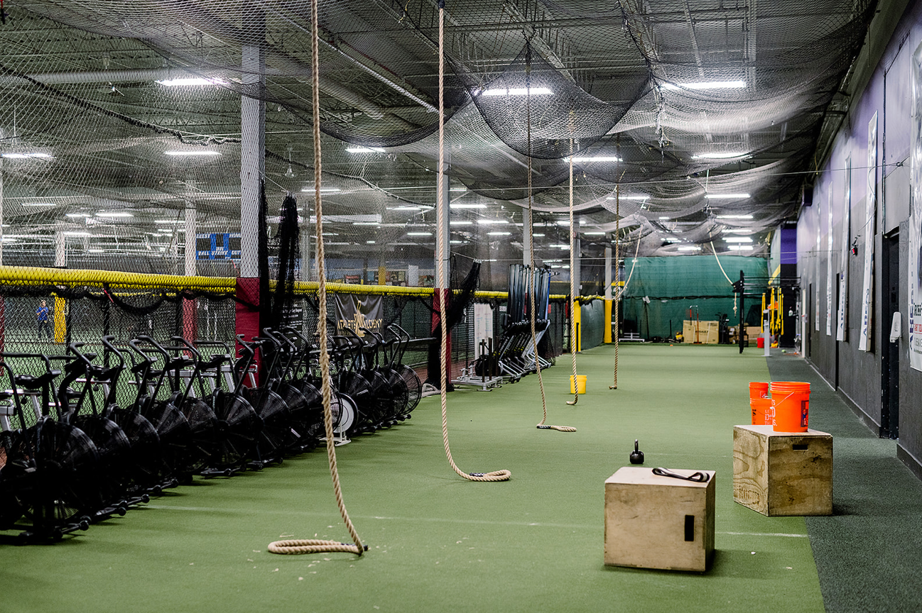 A large indoor gym with a lot of equipment and ropes hanging from the ceiling.