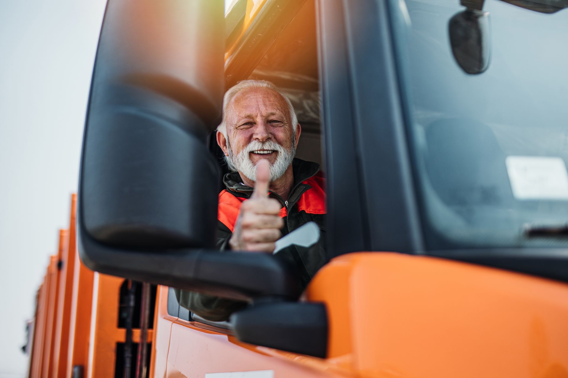 Truck driver gives a thumbs-up from an orange service truck cab. Truck driver gives a thumbs-up from an orange service truck cab.