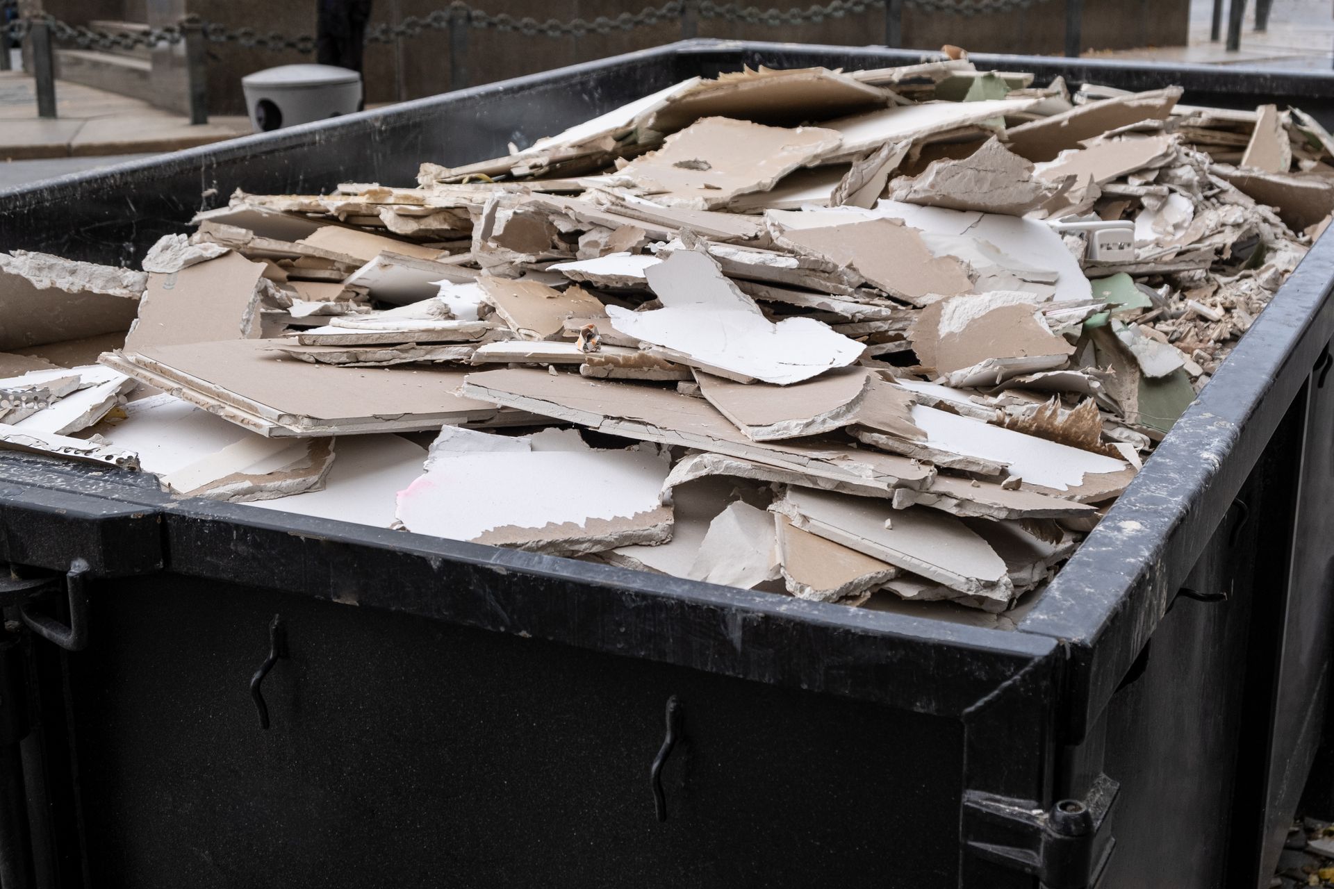 a dumpster with construction debris, including drywall and lumber