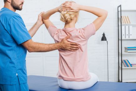 Un fisioterapista aiuta una paziente ad allungare le spalle in una clinica.