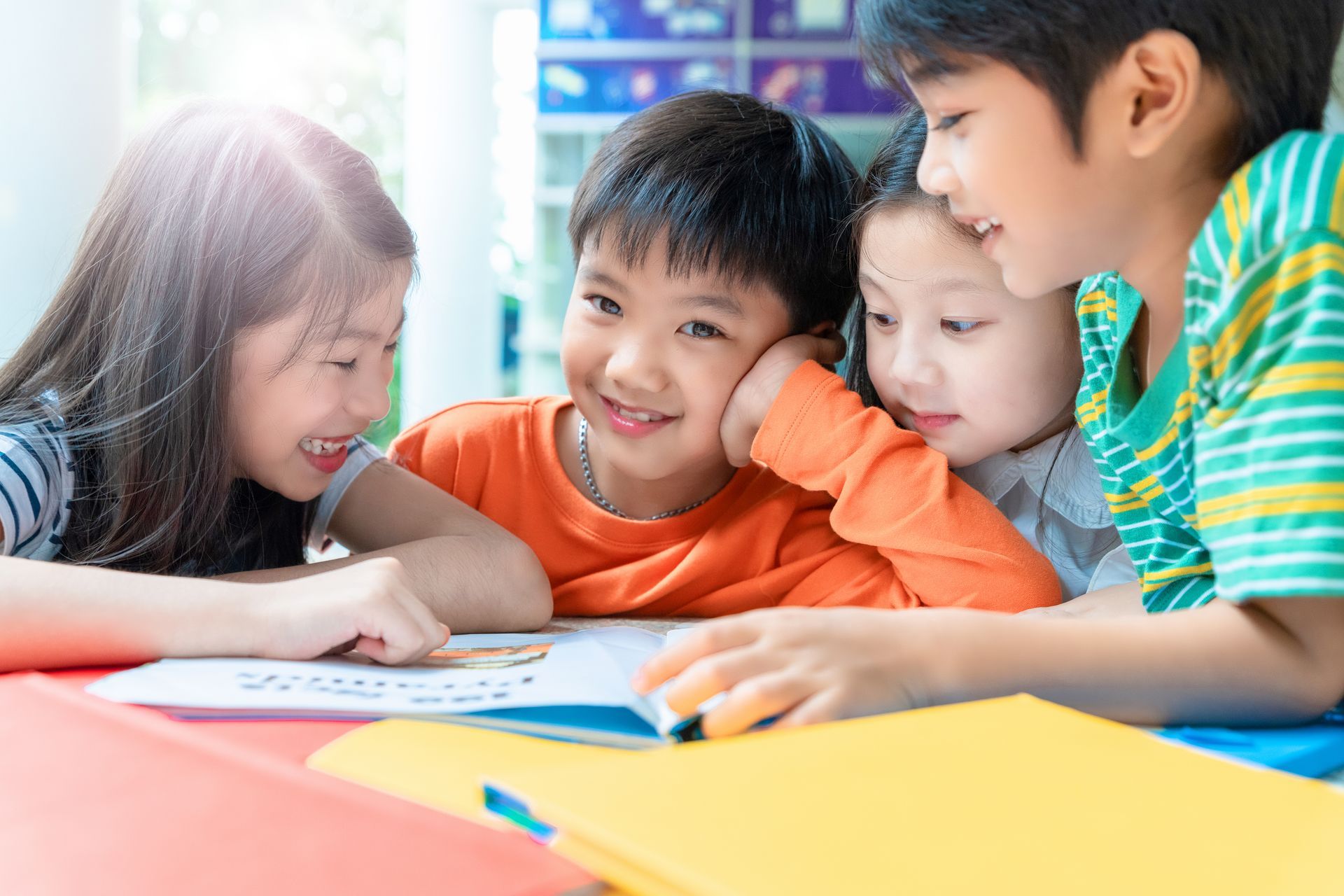 Group of children writing on a paper while discussing what's on the paper