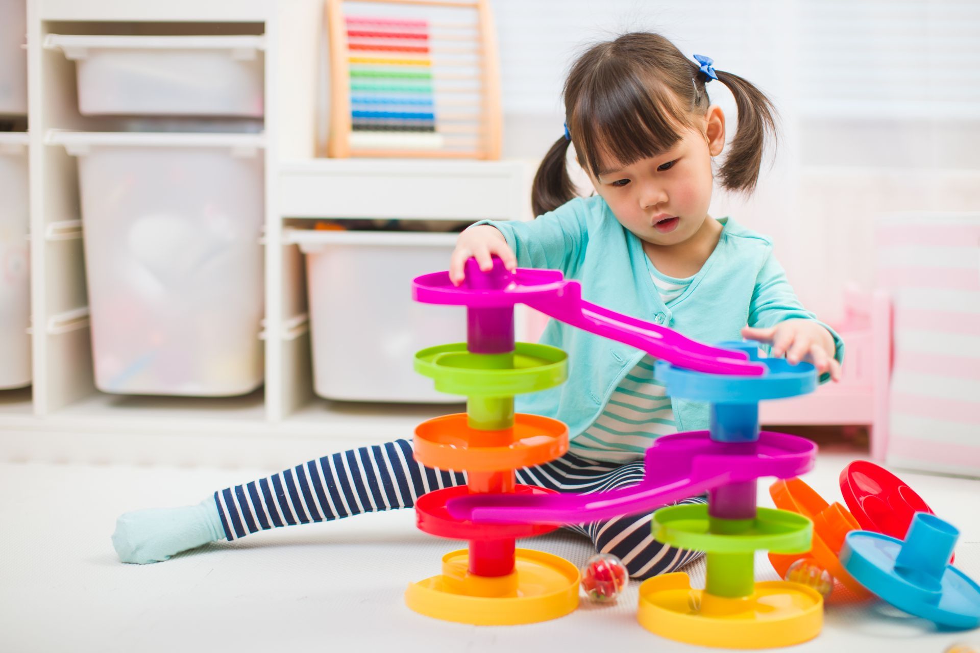 Little girl playing with a colorful sliding toy