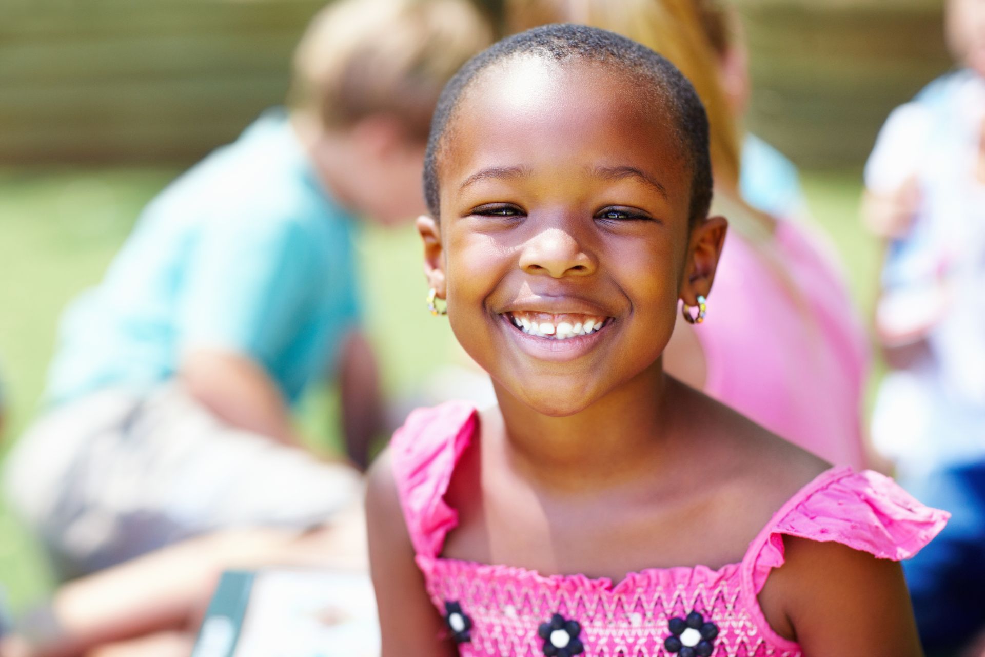 Smiling girl with a group of children playing in the background