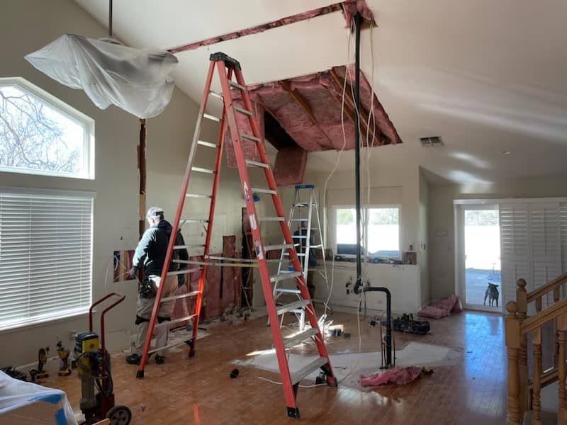 A man is standing on a ladder in a living room