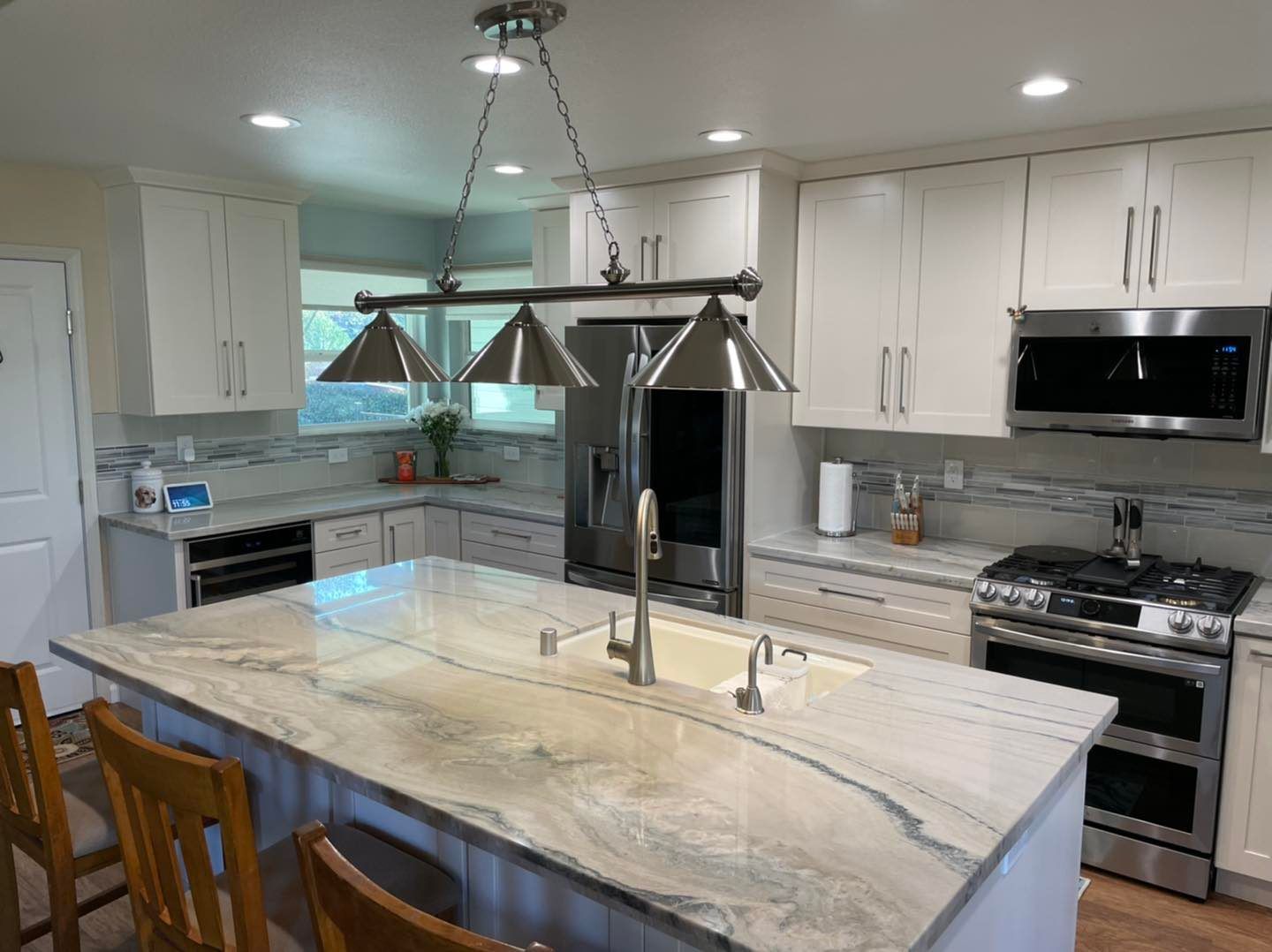 A kitchen with white cabinets and stainless steel appliances and a large island.