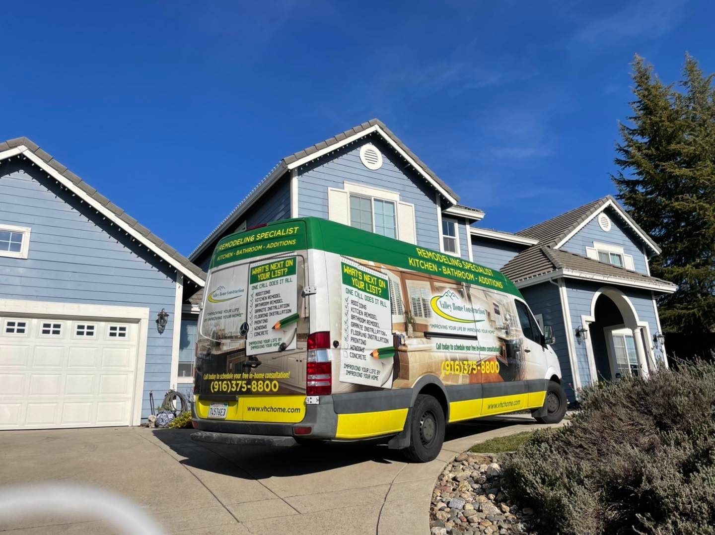 A white and yellow van is parked in front of a house.