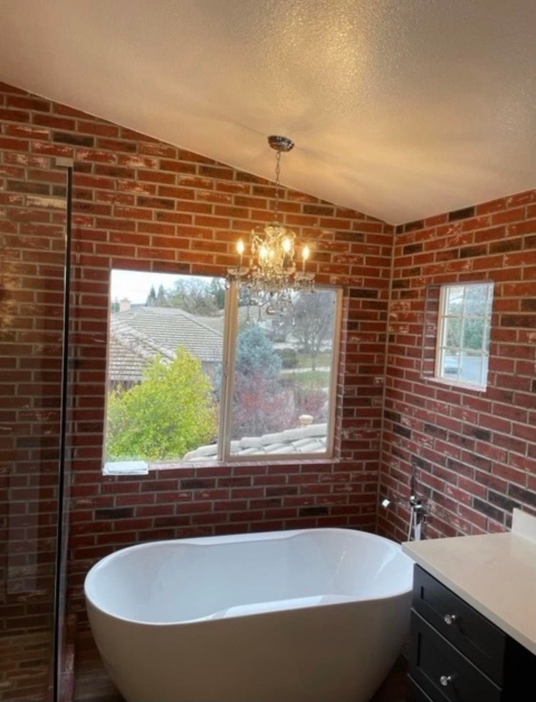 A bathroom with a bathtub and a brick wall.