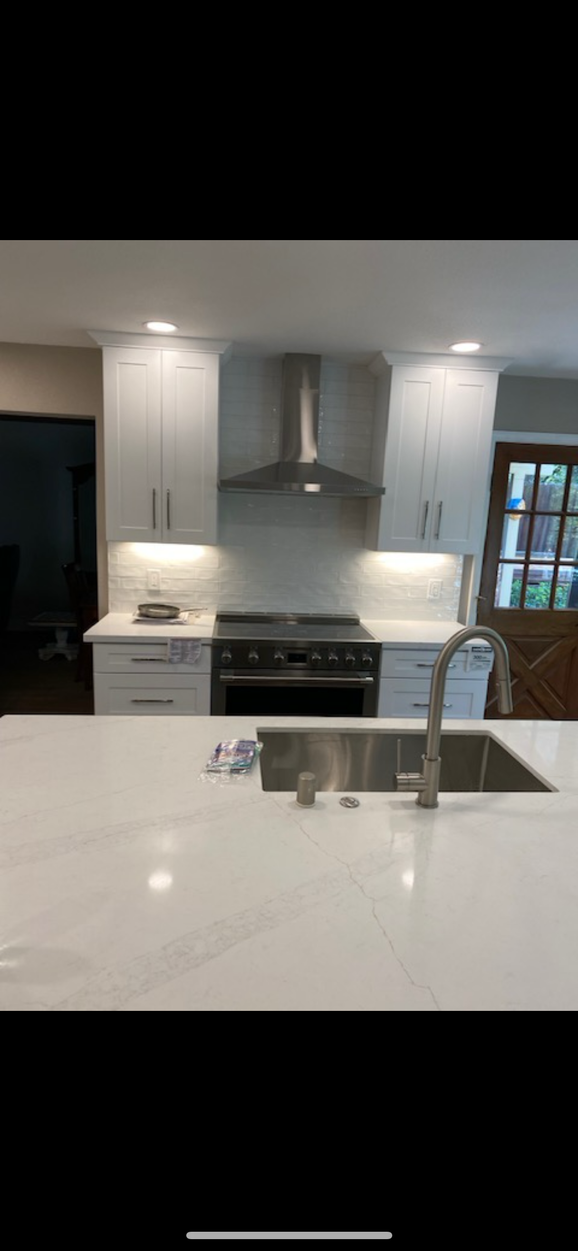 Modern kitchen with white cabinets, stainless steel appliances, and a large island with a sink.
