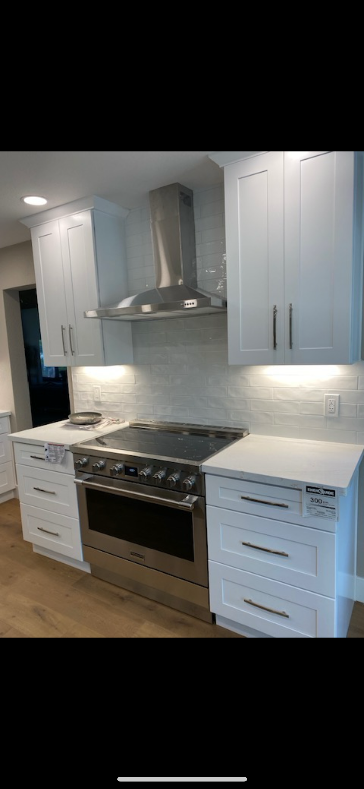 A modern kitchen with white cabinets, a stainless steel range, and a matching range hood.