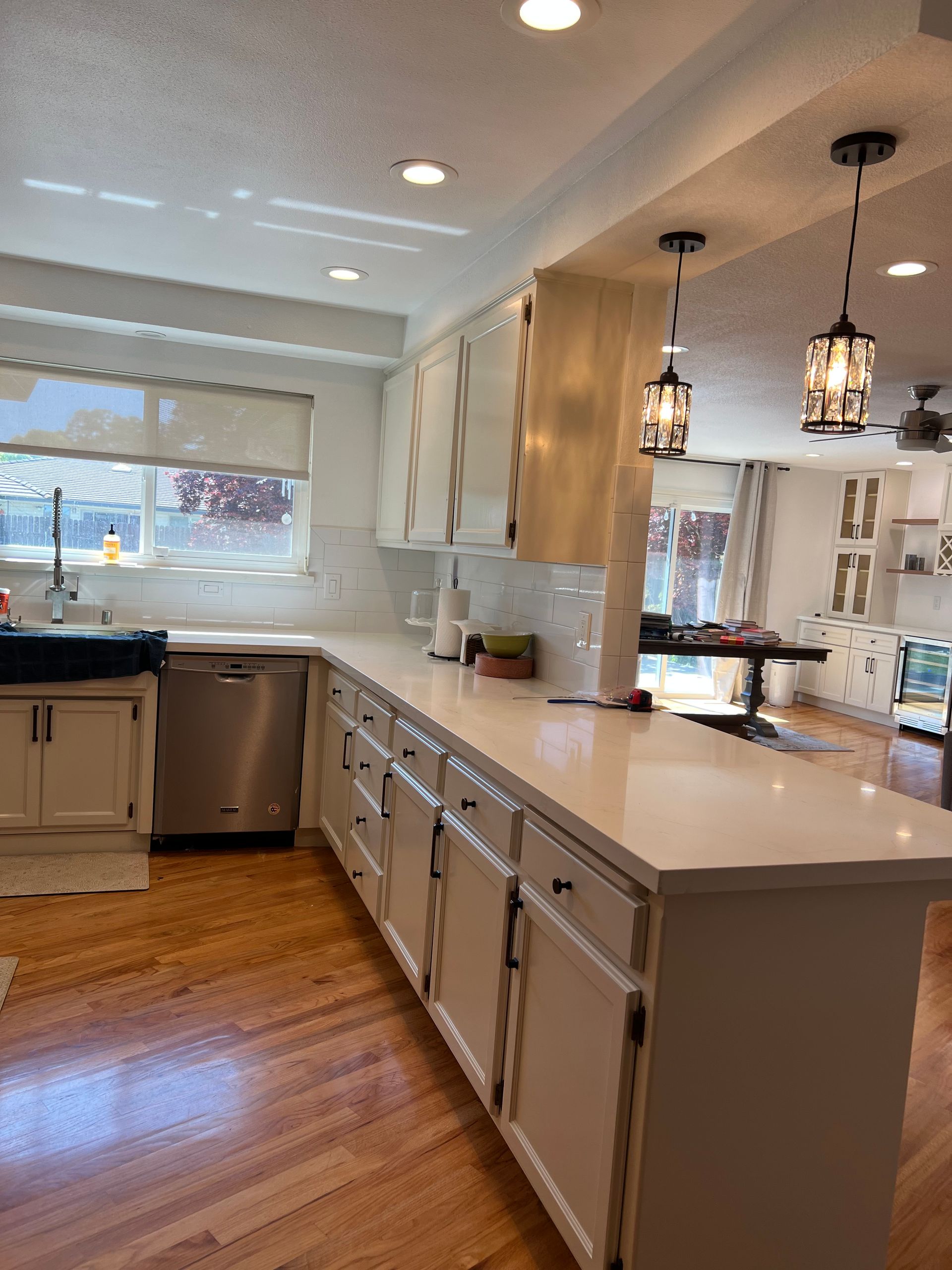 A modern kitchen with white cabinets, stainless steel appliances, and light wood floors.